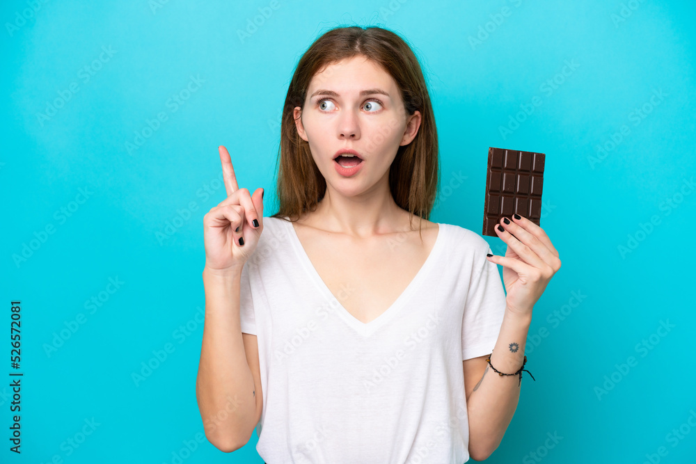 Young English woman with chocolat isolated on blue background thinking an idea pointing the finger up Young English woman with chocolat isolated on blue background thinking an idea pointing the finger up