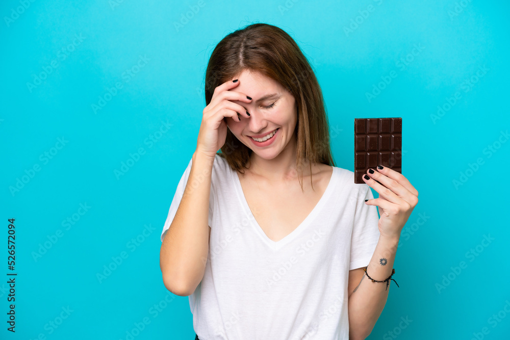 Young English woman with chocolat isolated on blue background laughing Young English woman with chocolat isolated on blue background laughing