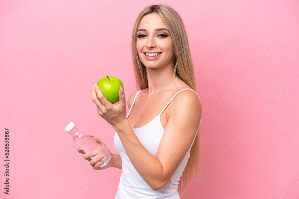 Pretty blonde woman isolated on pink background with an apple and with a bottle of water Pretty blonde woman isolated on pink background with an apple and with a bottle of water