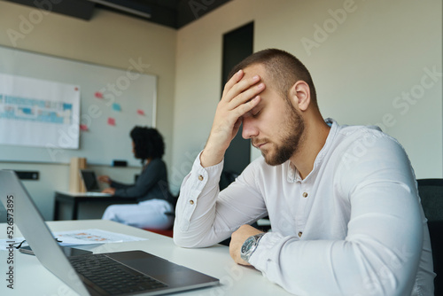 Tired man with closed eyes sitting at his desk