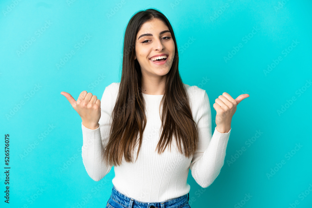 Young caucasian woman isolated on blue background with thumbs up gesture and smiling Young caucasian woman isolated on blue background with thumbs up gesture and smiling