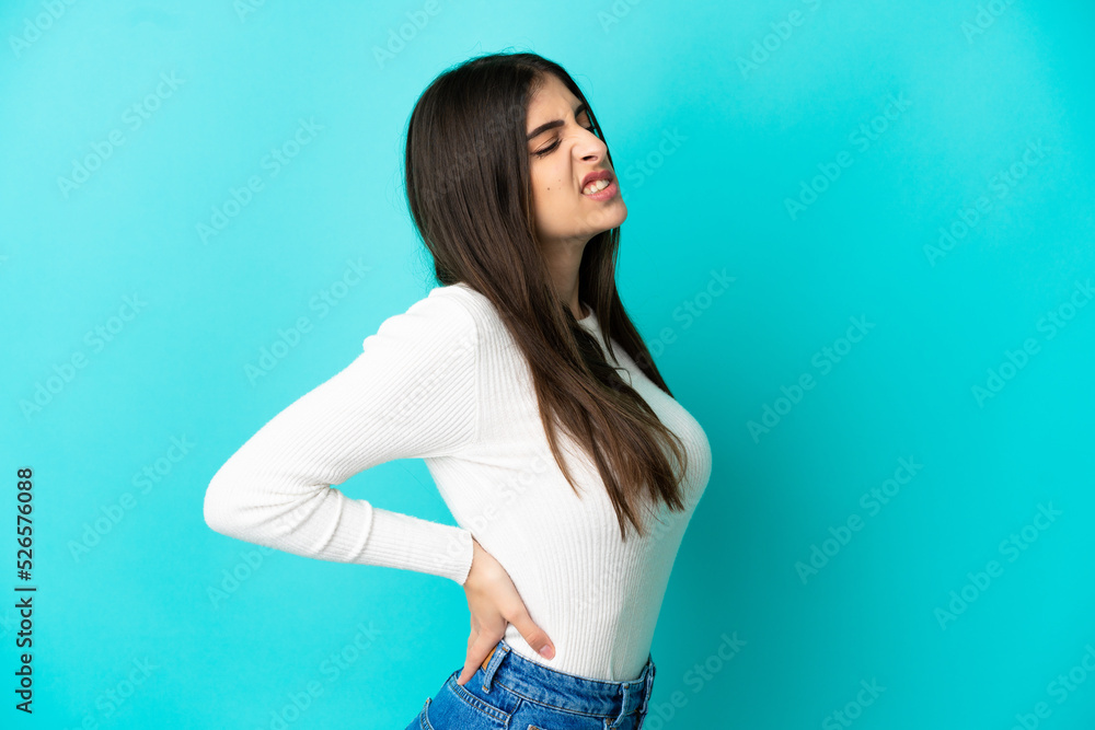 Young caucasian woman isolated on blue background suffering from backache for having made an effort Young caucasian woman isolated on blue background suffering from backache for having made an effort