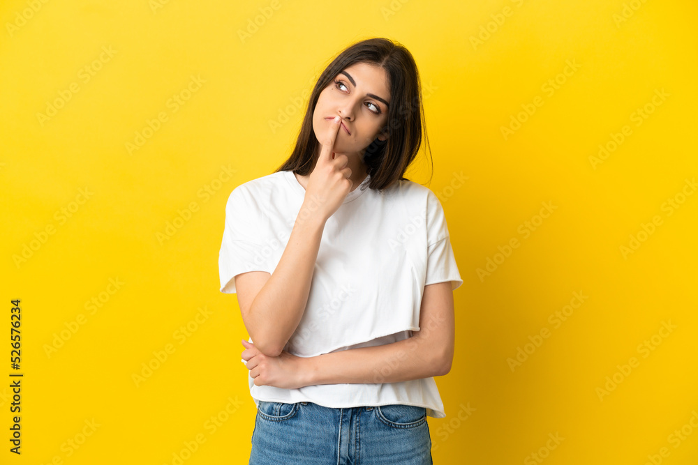 Young caucasian woman isolated on yellow background having doubts while looking up Young caucasian woman isolated on yellow background having doubts while looking up
