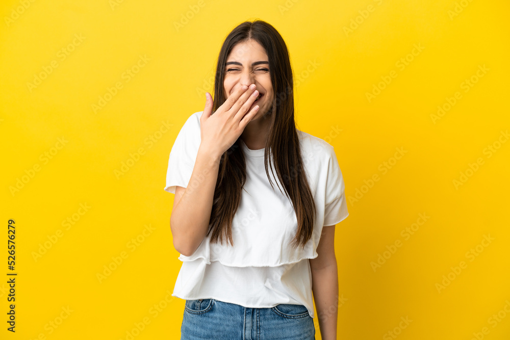 Young caucasian woman isolated on yellow background happy and smiling covering mouth with hand Young caucasian woman isolated on yellow background happy and smiling covering mouth with hand