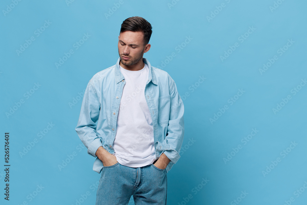 Pensive upset thoughtful tanned handsome man in casual basic t-shirt hold hands on jeans pocket posing isolated on blue studio background. Copy space Banner Mockup. People emotions Lifestyle concept Pensive upset thoughtful tanned handsome man in casual basic t-shirt hold hands on jeans pocket posing isolated on blue studio background. Copy space Banner Mockup. People emotions Lifestyle concept
