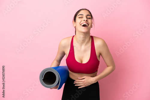 Young sport caucasian woman going to yoga classes while holding a mat smiling a lot