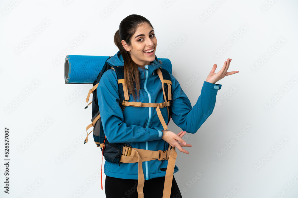 Young mountaineer man with a big backpack over isolated background extending hands to the side for inviting to come Young mountaineer man with a big backpack over isolated background extending hands to the side for inviting to come
