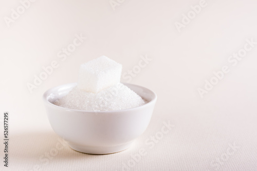 Bowl with granulated sugar and a cube on a pink background. Choosing between types of sugar