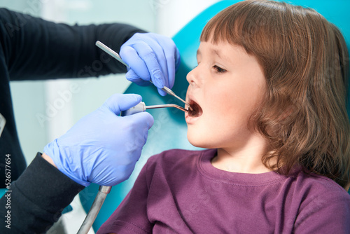 Doctor examining oral cavity of female child with dental instruments