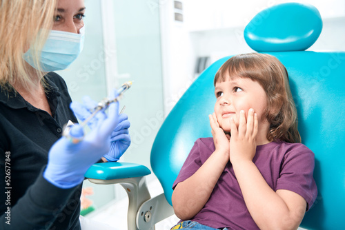 Scared child looking at female doctor before anesthetic injection