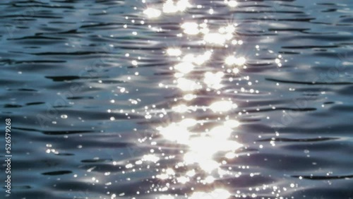 sunset n sunrise reflection on water surface, texture of ocean slow motion moving with small clam waves. shining light from sun on sea water. relaxing time in the morning scenery. blurry background