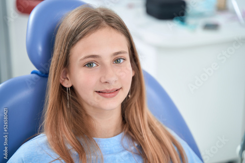 Calm adolescent girl sitting in dentist office