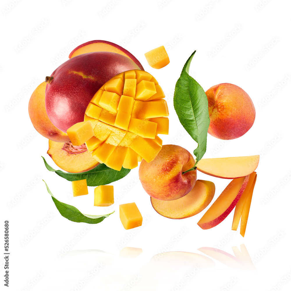 Fresh ripe whole and sliced mango and peaches with green leaves falling in the air Fresh ripe whole and sliced mango and peaches with green leaves falling in the air