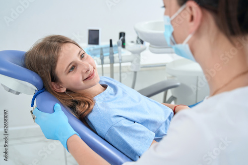 Joyous teenager gazing at pedodontist during consultation