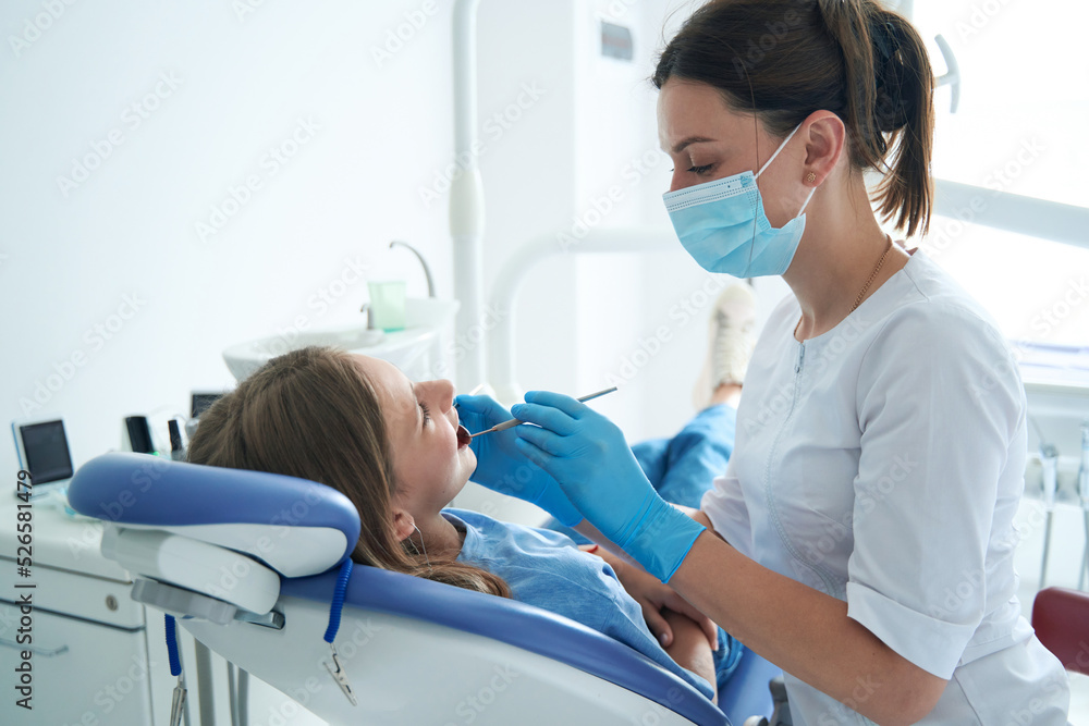 Pediatric dentist examining teeth of teenage patient Pediatric dentist examining teeth of teenage patient