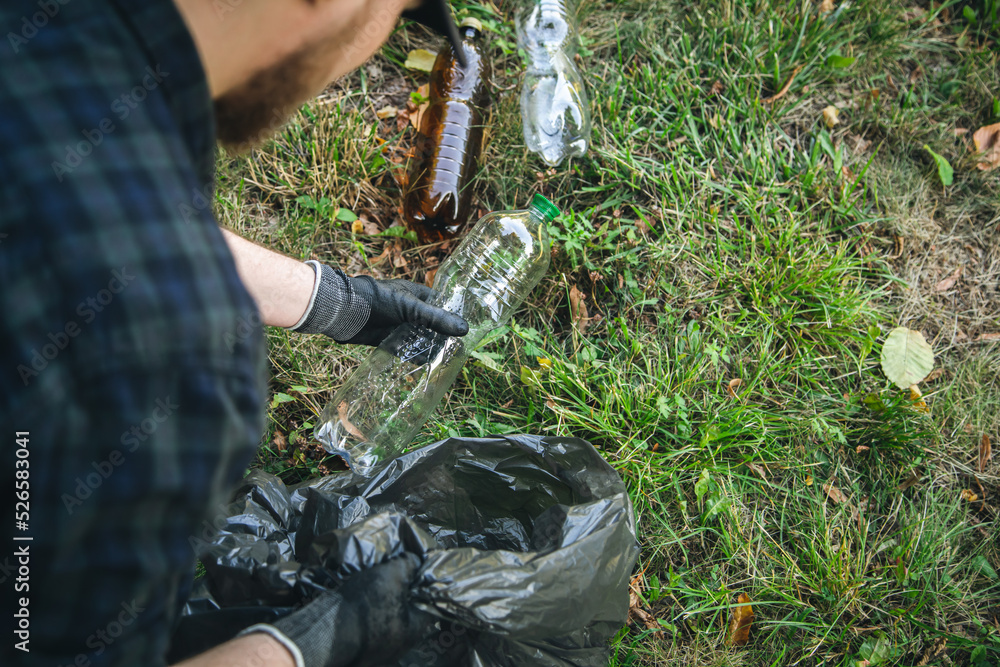 Obraz premium Close-up, a plastic bottle in a male hand, cleaning up nature.