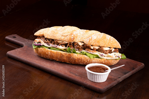 Shredded beef brisket sandwich with barbecue sauce on wooden board viewed from an angle