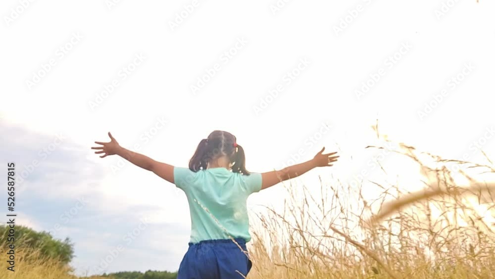 Happy little girl runs among the tall grass, in the field, in the summer, rear view Happy little girl runs among the tall grass, in the field, in the summer, rear view
