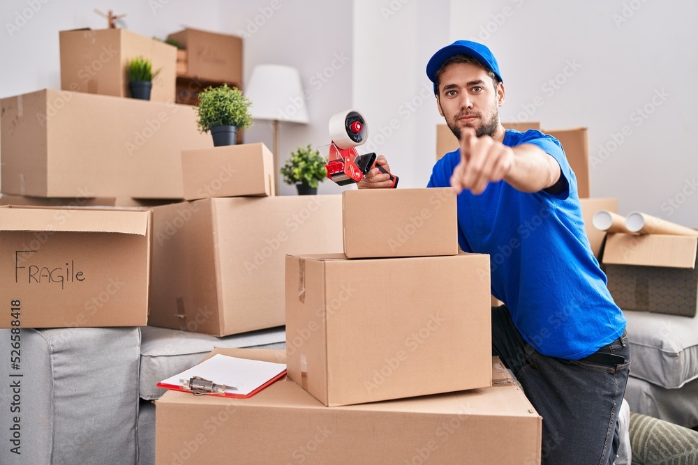 Hispanic man with beard working moving boxes pointing with finger to the camera and to you, confident gesture looking serious Hispanic man with beard working moving boxes pointing with finger to the camera and to you, confident gesture looking serious