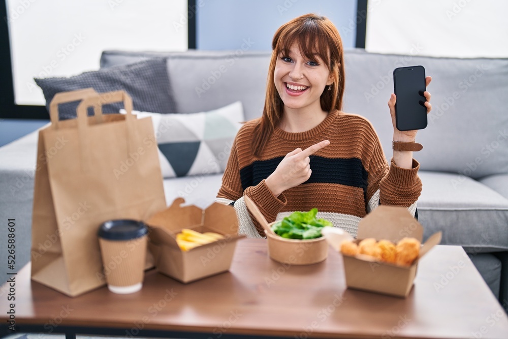 Young beautiful woman eating delivery food at the living room smiling happy pointing with hand and finger