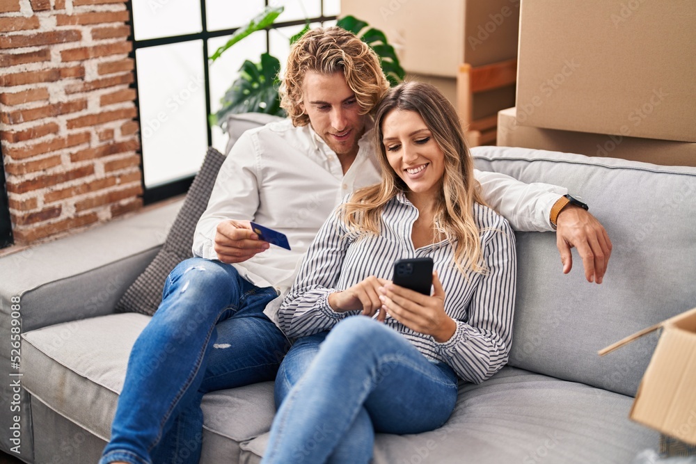 Man and woman couple using smartphone and credit card at new home Man and woman couple using smartphone and credit card at new home