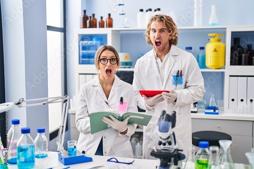 Two people working at scientist laboratory angry and mad screaming frustrated and furious, shouting with anger. rage and aggressive concept.