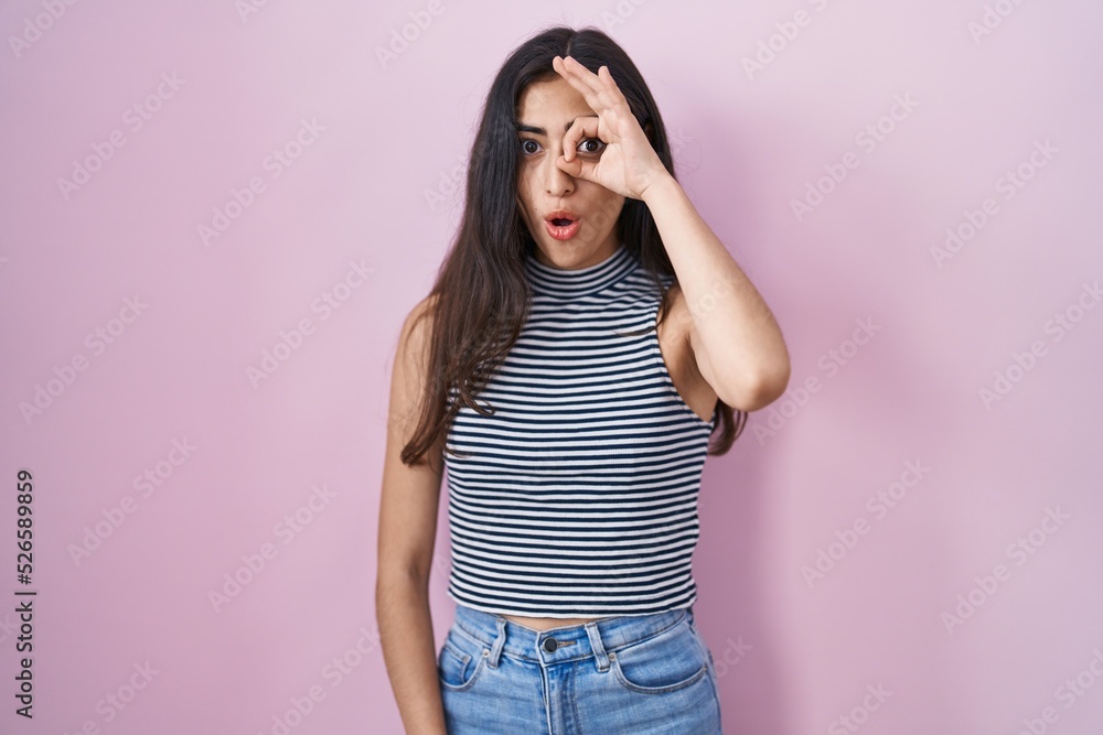 Young teenager girl wearing casual striped t shirt doing ok gesture shocked with surprised face, eye looking through fingers. unbelieving expression. Young teenager girl wearing casual striped t shirt doing ok gesture shocked with surprised face, eye looking through fingers. unbelieving expression.