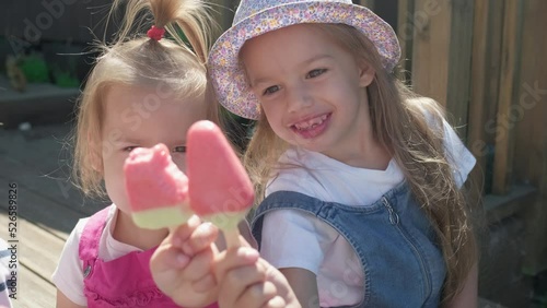 Two Sisters Children enjoys delicious ice cream cone. Child eating watermelon popsicle. Kids Siblings snack sweets in Home Garden. Summer holiday Hot weather Sunny Day. Childhood, Food Candy Friends