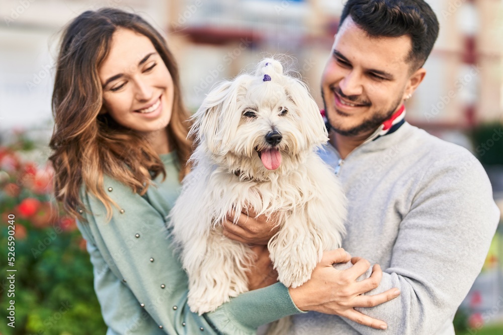 Man and woman holding dog hugging each other at park Man and woman holding dog hugging each other at park