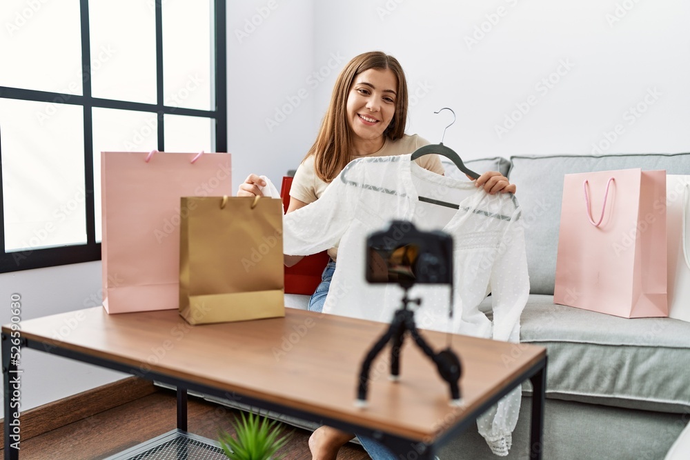 Young hispanic woman having video call showing clothes at home Young hispanic woman having video call showing clothes at home