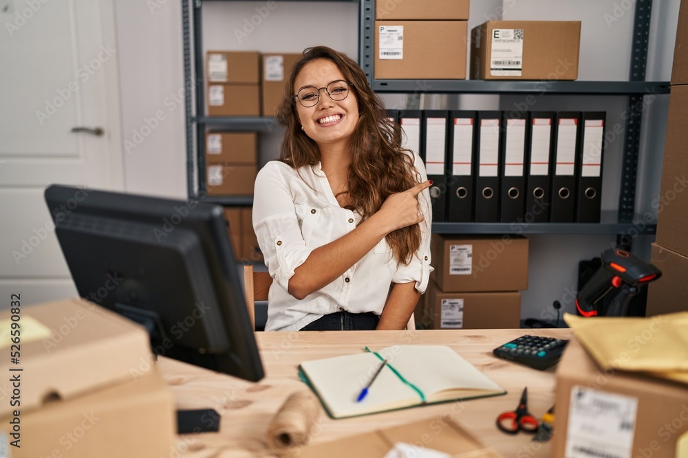 Young hispanic woman working at small business ecommerce cheerful with a smile on face pointing with hand and finger up to the side with happy and natural expression Young hispanic woman working at small business ecommerce cheerful with a smile on face pointing with hand and finger up to the side with happy and natural expression
