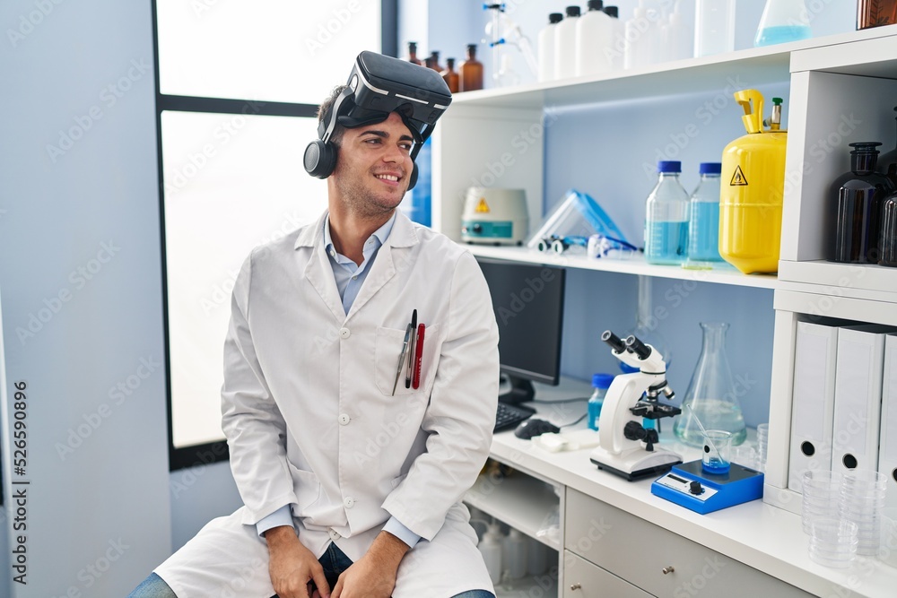 Young hispanic man working at scientist laboratory wearing vr glasses looking to side, relax profile pose with natural face and confident smile. Young hispanic man working at scientist laboratory wearing vr glasses looking to side, relax profile pose with natural face and confident smile.