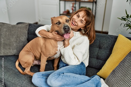 Young caucasian woman smiling confident hugging dog sitting on sofa at home