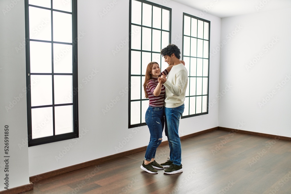 Young hispanic couple smiling happy dancing at empty new home. Young hispanic couple smiling happy dancing at empty new home.
