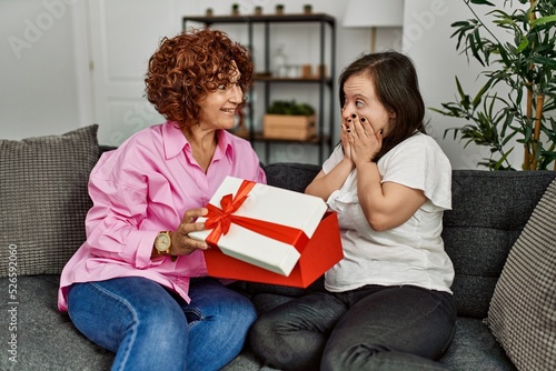Mature mother and down syndrome daughter at home giving a surprise gift to the other