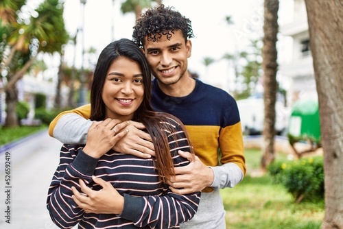 Young latin couple smiling happy and hugging at the city.