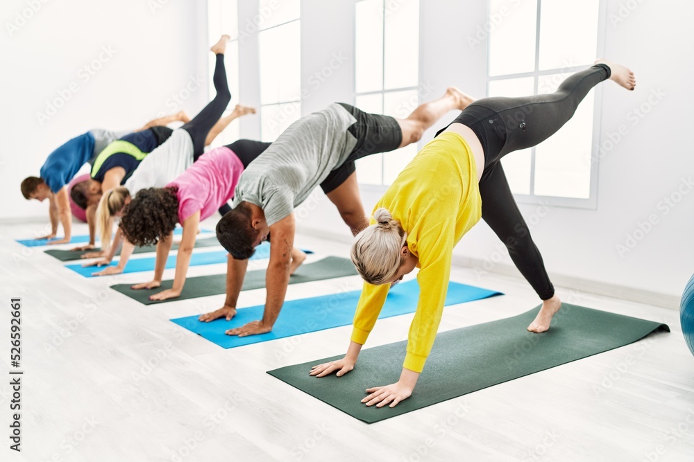 Group of young people concentrated training yoga at sport center.