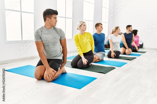 Group of young people concentrated stretching at sport center.