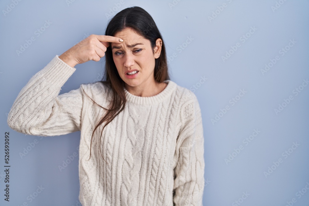 Young brunette woman standing over blue background pointing unhappy to pimple on forehead, ugly infection of blackhead. acne and skin problem Young brunette woman standing over blue background pointing unhappy to pimple on forehead, ugly infection of blackhead. acne and skin problem