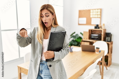 Blonde business woman at the office pointing down with fingers showing advertisement, surprised face and open mouth © Krakenimages.com