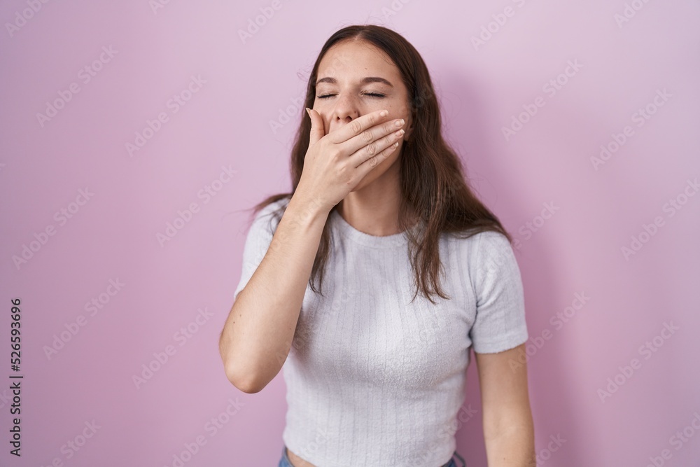 Young hispanic girl standing over pink background bored yawning tired covering mouth with hand. restless and sleepiness. Young hispanic girl standing over pink background bored yawning tired covering mouth with hand. restless and sleepiness.
