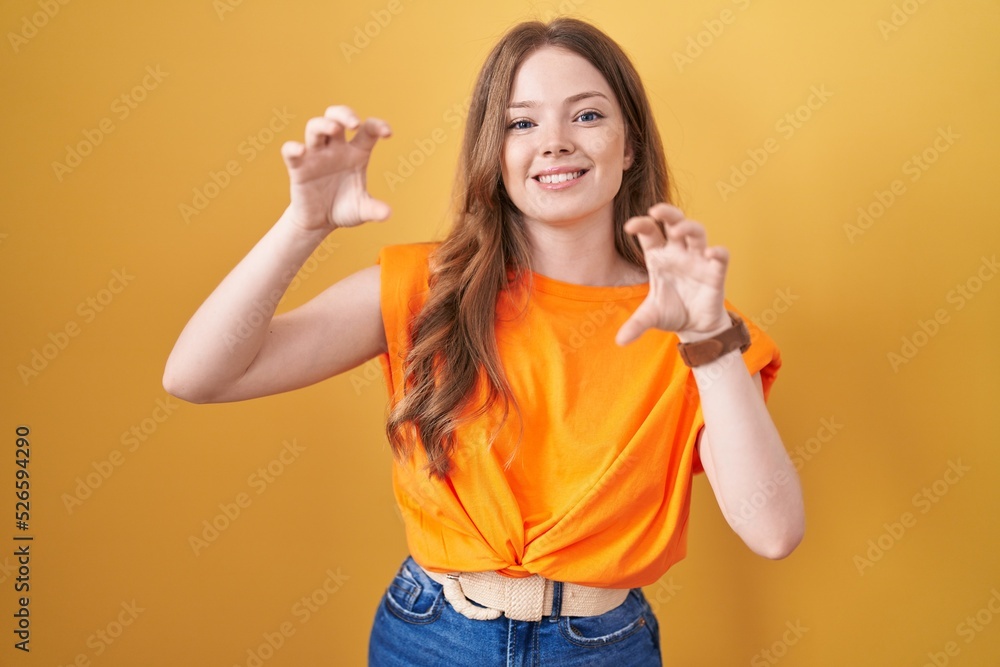 Caucasian woman standing over yellow background smiling funny doing claw gesture as cat, aggressive and sexy expression Caucasian woman standing over yellow background smiling funny doing claw gesture as cat, aggressive and sexy expression