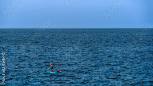 One man practicing paddle board or paddle surfing on a sunny day in the middle of the sea