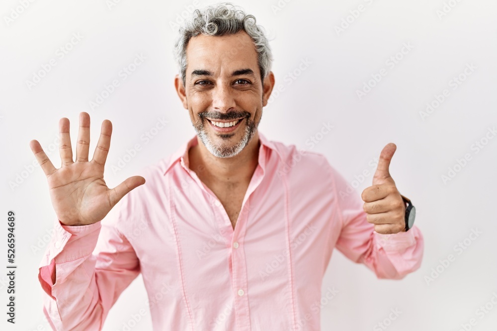 Middle age hispanic man standing over isolated background showing and pointing up with fingers number six while smiling confident and happy. Middle age hispanic man standing over isolated background showing and pointing up with fingers number six while smiling confident and happy.