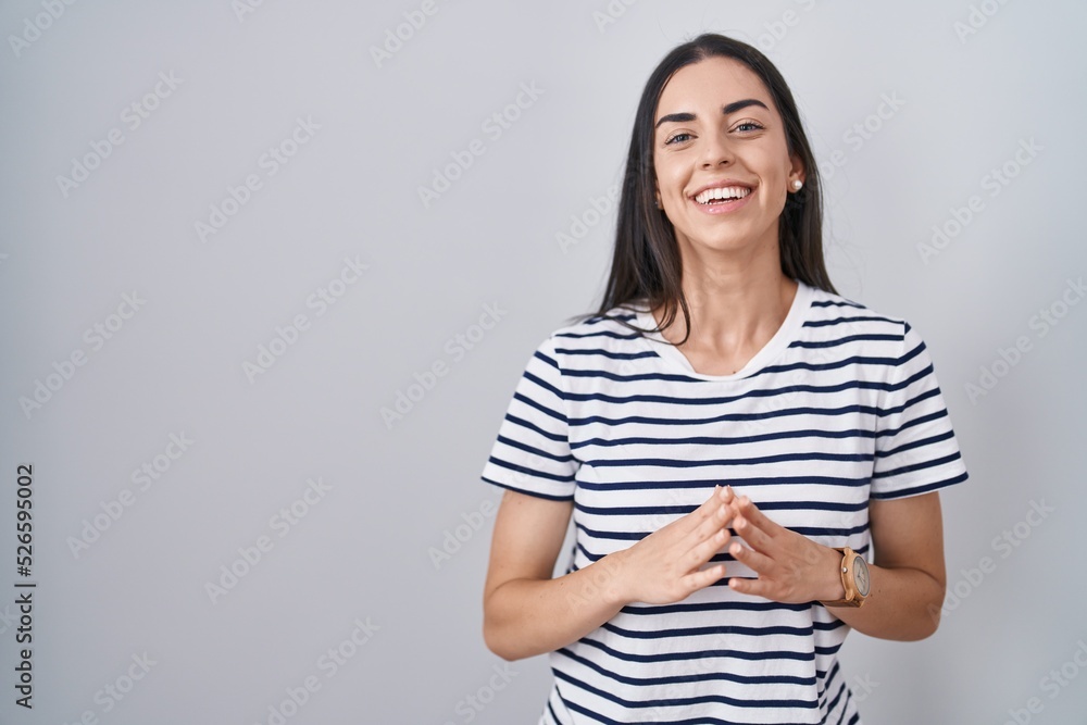 Young brunette woman wearing striped t shirt hands together and fingers crossed smiling relaxed and cheerful. success and optimistic Young brunette woman wearing striped t shirt hands together and fingers crossed smiling relaxed and cheerful. success and optimistic