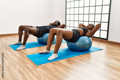 Young african american sporty couple training pilates using fitball at sport center.