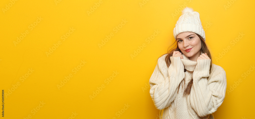 Pretty young woman in autumn sweater and hat on yellow background with space for text Pretty young woman in autumn sweater and hat on yellow background with space for text