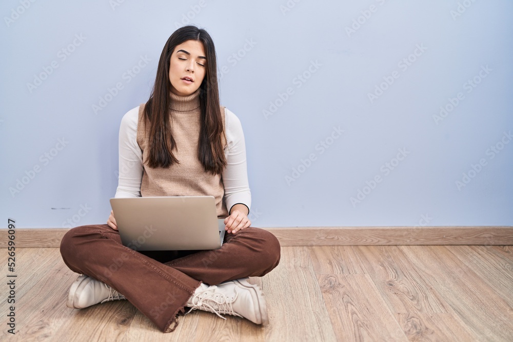 Young brunette woman working using computer laptop sitting on the floor looking sleepy and tired, exhausted for fatigue and hangover, lazy eyes in the morning. Young brunette woman working using computer laptop sitting on the floor looking sleepy and tired, exhausted for fatigue and hangover, lazy eyes in the morning.
