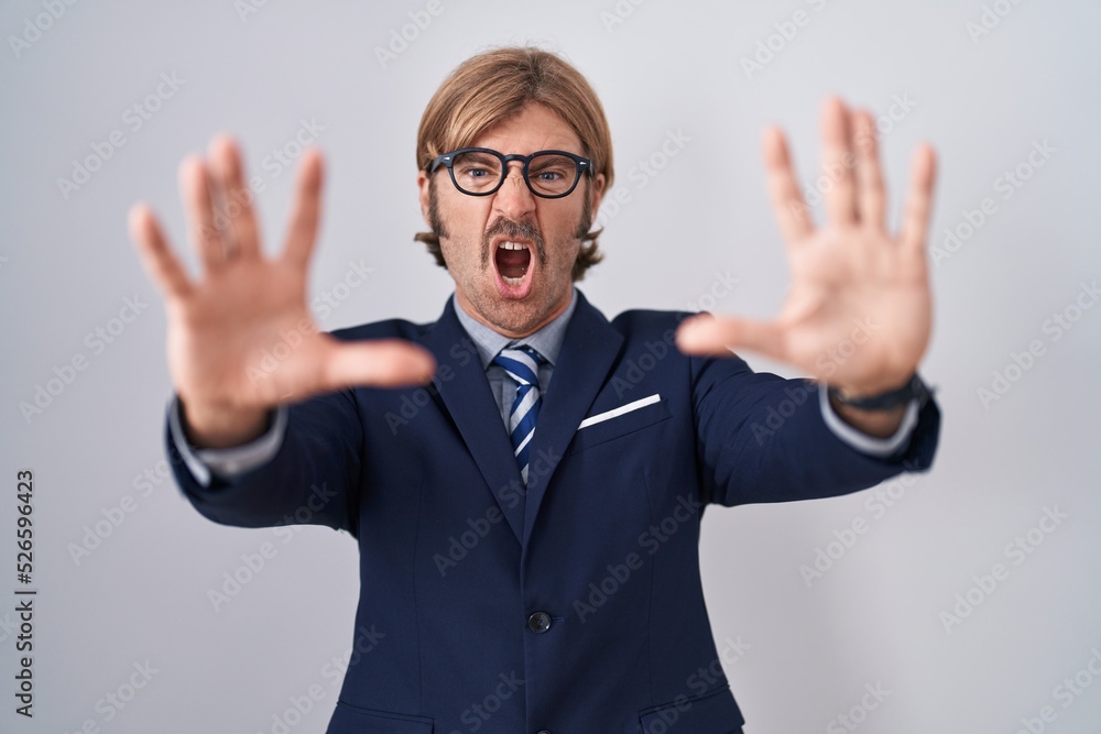 Caucasian man with mustache wearing business clothes doing stop gesture with hands palms, angry and frustration expression Caucasian man with mustache wearing business clothes doing stop gesture with hands palms, angry and frustration expression