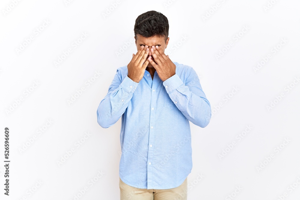 Young hispanic man wearing business shirt standing over isolated background rubbing eyes for fatigue and headache, sleepy and tired expression. vision problem Young hispanic man wearing business shirt standing over isolated background rubbing eyes for fatigue and headache, sleepy and tired expression. vision problem